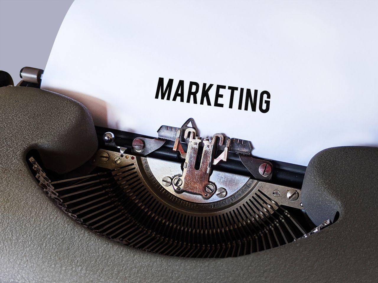 Vue rapprochée d'une machine à écrire vintage avec le mot Marketing sur le papier, évoquant une ambiance business rétro.